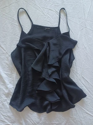 Svart volangtop🤍🤍 - Säljer en svart linnetopp från Tally Weijl med tunna axelband och stora volangdetaljer framtill.   Jag tyckte axelbanden var lite långå så klippte den och sydde ihop de. 