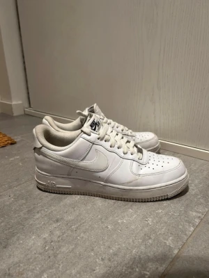 Vita Flyease Nike Air Force 1 sneakers - Klassiska vita Flyease Nike Air Force 1 sneakers i lågt utförande. Skorna har en stilren design med perforerad tå, vit sula och Nike-logga på sidan. Tillverkade i läder med textildetaljer och snörning framtill. Perfekta för en clean och tidlös look. Väldigt bra skick nästan ny bara använda nästan 5 gånger