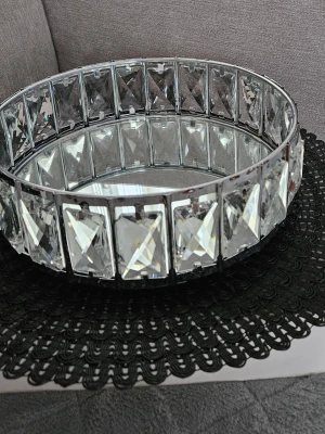 Rund spegelbricka med kristalldetaljer - Säljer en rund spegelbricka med kant av stora, rektangulära kristalliknande glasbitar. Perfekt som dekoration på bordet eller för att ställa ljus och småprylar på. Ger ett lyxigt och glittrande intryck i rummet.