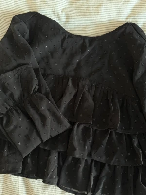 volangblus  - Snygg svart blus med små prickar och flera volanglager. Blusens knäppe har tyvärr gått sönder🖤