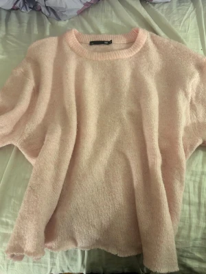 Ljusrosa stickad tröja från lager 157 - Mysig ljusrosa stickad tröja från lager 157 med rund halsringning och avslappnad passform. Tröjan har långa ärmar och är gjord i ett mjukt, fluffigt material som känns skönt mot huden. Perfekt för lager på lager och en söt vardagslook.
