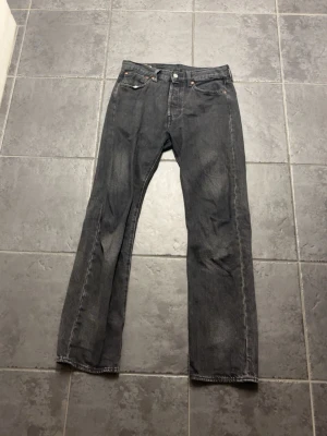 Grå raka jeans från Levi's - Säljer ett par svarta Levi's jeans med rak passform och klassisk femficksdesign. Jeansen har en diskret tvättad look och är tillverkade i slitstark denim. Perfekta för dig som gillar en avslappnad och tidlös stil. W31 L32!