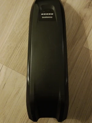 Shimano Steps BT-E8010 504Wh Batteri - Elektronisk kontaktadapter i svart plast med flera stift och robust design. Passar för anslutning av elektronikkomponenter och har en rektangulär form med skyddande lock och skruvfästen. Perfekt för dig som behöver en extra anslutning till din utrustning.