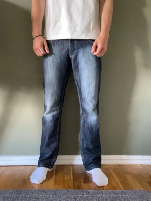 Vintage jeans - Snygga mörkblå jeans med lite bootcut och ljusa slitningar framtill och bakfickor med dekorativa sömmar. Jeansen har klassisk femficksdesign och normal midja. Perfekta för en avslappnad och trendig look.