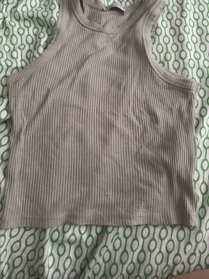 Linné topp  - Snygg grön ribbad linnetopp med hög hals och ärmlös design. Perfekt till jeans eller kjol för en chill och trendig look. Mjuk och stretchig bomullskvalitet som sitter skönt på kroppen.