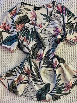Zizzi ”Cavargas” mönstrad sommarblus (Stl S / 42-44) - Säljer en jättefin mönstrad blus med tropiska blad och blommor från märket Zizzi.. Perfekt boho-sommarstil! Snygg V-ringning och ett väldigt fint fall i tyget med bekväm stretch. Se exakta mått på bilderna! * Märke/Modell: Zizzi Cavargas Blouse * Storlek: S från Zizzi (Obs! Plus size-märke, så den passar bäst för dig som har storlek 42 eller 44) * Mått: Längd ca 71cm * Material: 97% polyester, 3% elastan (lättskött och skrynkelfritt med stretch) * Skick: Toppenskick Köparen står för frakten. 🌸