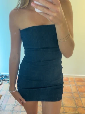 Jeansklänning från Zara - Kort festklänning från zara i jeansmaterial. Inga axelband, passar perfekt på sommarfest. Storlek Small, aldrig använd.