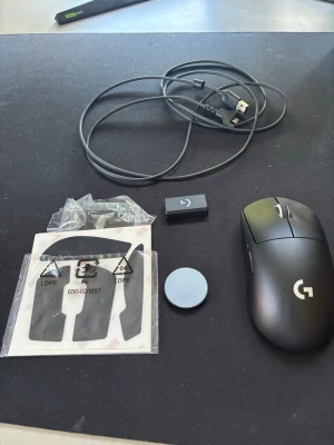 Logitech G Pro X Superlight muspaket - Säljer en svart Logitech G Pro X Superlight gamingmus med tillbehör som USB-kabel, dongel, extra glidytor och en rund vikt. Perfekt för gaming och e-sport med trådlös och lätt design. Allt är svart och tillverkat i plast.
