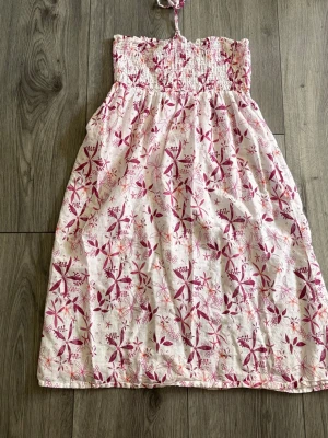 Vit och rosa blommig sommarklänning - Söt axelbandslös klänning i vitt med rosa blommigt mönster. Perfekt för varma dagar. Lätt och luftig modell med avslappnad passform. Kan vara använd som klänning eller kjol. Skriv för mått om det behövs.