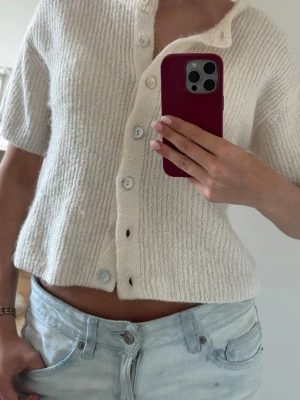 Vit kortärmad stickad kofta  - Superfin krämvit stickad kofta med korta ärmar och ribbad struktur från Gina Tricot. Säljer då den it kommer till användning längre, endast använd ett par fåtal gånger så i bra skick. Så snygg till sommaren bla. Pris kan diskuteras, skriv om frågor💕
