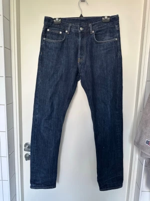 Arket Mörkblå raka jeans med fem fickor EUR 31/32 - Säljer ett par klassiska mörkblå jeans med rak passform och fem fickor. Jeansen har kontrastsömmar och bälteshällor. Tillverkade i kraftigt denimtyg, perfekta för en clean och tidlös look.