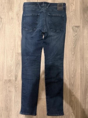 Replay Anbass Hyperflex Jeans Mörkblå W30 - Slim Fit - Replay Anbass Hyperflex mörkblå jeans i stretchig Hyperflex denim med slim fit passform som sitter snyggt och bekvämt och funkar till allt, storlek W30/L okänd (innerlapp avklippt), midja 39,5 cm, ytterbenslängd 102 cm, benöppning 15 cm, modellen är 185cm & väger 65kg, i fint skick.