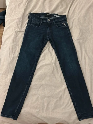 Replay mörkblå slim fit  - Snygga mörkblå slim fit replay jeans med klassisk femficksdesign och raka ben. Jeansen har en stilren look och passar perfekt till vardagsstilen. Materialet är stretchigt denim som ger en bekväm passform.(använda ett fåtal gånger)
