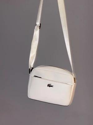 Vit axelväska från Lacoste - Snygg vit axelväska från Lacoste med justerbart band och silverfärgade dragkedjor. Väskan har en stilren design med Lacoste-loggan framtill, ett huvudfack och en mindre ficka både fram och bak. Perfekt för att bära det viktigaste med stil.