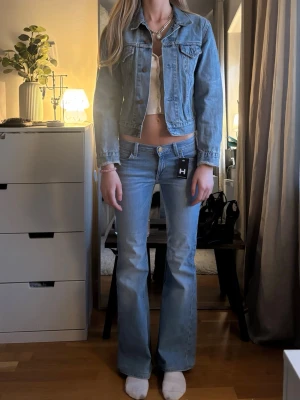 Ljusblå jeansjacka Levi's - Snygg ljusblå jeansjacka från Levi's med klassisk krage, bröstfickor med lock och knappar framtill. Jackan har en rak, kortare passform och är tillverkad i äkta denim. Perfekt att slänga över en topp för en cool look.