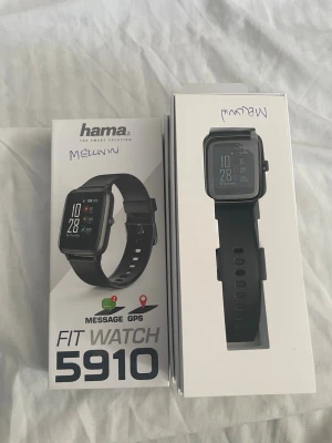Hama Fit Watch 5910 svart smartklocka - Snygg svart smartklocka från Hama, modell Fit Watch 5910. Klockan har en fyrkantig display, silikonarmband och GPS-funktion. Perfekt för att hålla koll på meddelanden och aktivitet direkt på handleden.