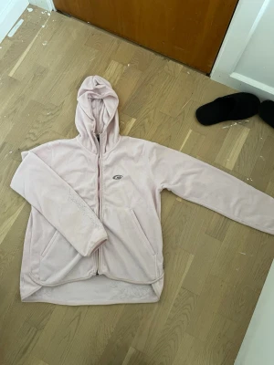 Ljusrosa fleecehoodie från Five Seasons - Mysig ljusrosa hoodie från Five Seasons i mjuk fleece. Modellen har dragkedja framtill, huva och två fickor. Perfekt för kyliga dagar när du vill vara både bekväm och snygg. Enkel logga på bröstet och stilren design.
