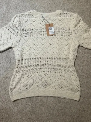 Vit stickad t shirt  - Denna t shirt är knappt andvönd och är så fin run till sommaren med en kjol ex. Den är stickad men blir ej varm i för den har hål mönster 