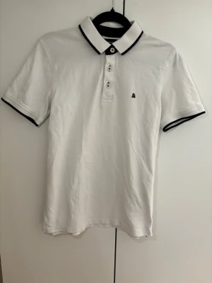 Jack & Jones vit pikétröjay XS - Oanvänd vit pikétröja från Jack & Jones i storlek XS. Klassisk modell med svarta detaljer, mycket fint skick utan defekter.