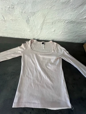Ljusrosa ribbad topp Gina Tricot - Supersnygg ljusrosa ribbad topp från Gina Tricot med lång ärm och fyrkantig ringning. Perfekt att styla med jeans eller kjol för en trendig look. Mjuk och stretchig i materialet för skön passform.