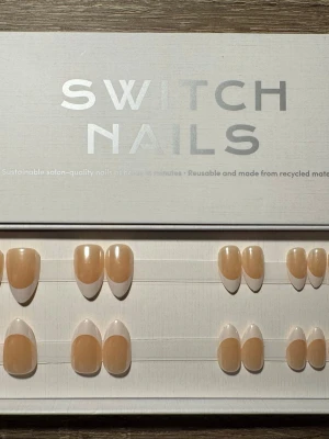 Switch Nails franska press-on naglar - Snygga press-on naglar från Switch Nails i klassisk fransk design. Naglarna har en naturlig nude bas med vit tipp och oval form. Tillverkade av återvunnet material och kan återanvändas. Perfekt för dig som vill ha salongskänsla hemma. Säljs utan tillbehör.