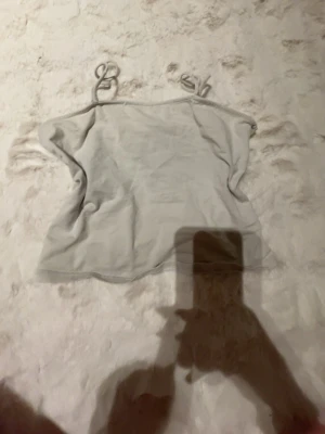 Ljusgrå croppad linnetopp H&M Divided - Säljer en enkel och stilren ljusgrå croppad linnetopp från H&M Divided. Toppen har tunna axelband och ärmlös design, perfekt för varma dagar eller som layering-piece. Mjuk och stretchig i materialet för en bekväm passform.