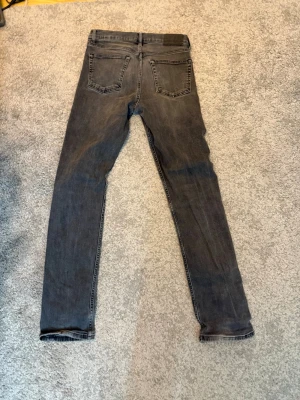 Grå slim fit jeans från J.Lindeberg - Snygga grå slim fit jeans från J.Lindeberg med klassisk femficksdesign och diskreta sömmar. Jeansen har en modern tvätt och är tillverkade i mjukt denimtyg som ger en skön passform. Perfekta för dig som gillar stilrena och tidlösa plagg.
