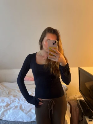 Svart långärmad topp med fyrkantig ringning - Snygg svart långärmad topp med fyrkantig ringning och figurnära passform. Perfekt att styla med både jeans och kjol för en trendig look. Tunn och stretchig kvalitet som känns skön mot huden.
