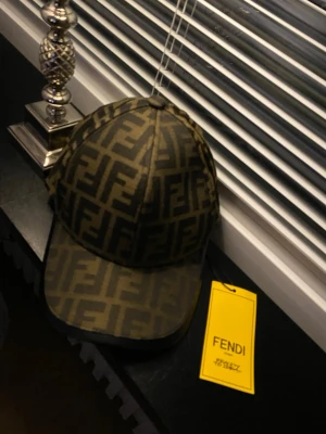 Fendi keps  - Säljer en snygg keps från Fendi med det klassiska FF-logomönstret i brunt och svart. Kepsen har böjd skärm och justerbar rem bak. Tillverkad i Italien och har en exklusiv känsla med märkets detaljer på insidan.