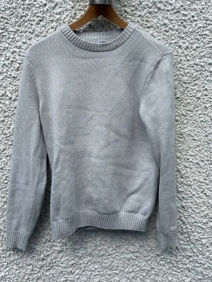 Ljusgrå stickad tröja från Dobber - Snygg ljusgrå stickad tröja från Dobber med rund halsringning och ribbade muddar vid ärmslut och nederkant. Enkel och stilren design som passar perfekt till jeans eller kjol. Mjuk och skön känsla, perfekt för kyligare dagar.