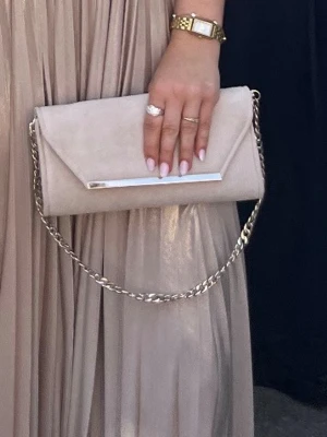 Beige kuvertväska med kedja - Stilren beige kuvertväska i mockaliknande material med kedjerem och metallist framtill. 