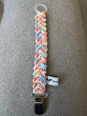 Virkad napphållare - Virkad, flerfärgad napphållare i pastellfärger. Virkad av mig i 100% bomullsgarn med metallclip och silikonring.  Mönsterskapare: animo.design 