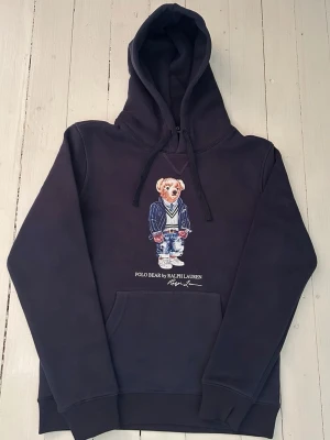 Ralph Lauren polo bear hoodie herr, storlek S  - Hej! Säljer denna riktigt schyssta polo bear hoodie från Ralph Lauren. Den är i storlek M men sitter en storlek litet och passar därför som en S. Den är endast använd någon enstaka gång och är därmed i ett nyskick. Om den ser fläckig/solblekt ut är det endast pga dåligt fotoljus. Original lappar och påse finns kvar och medföljer naturligtvis vid köp. Jag fraktar alltid snabbt! Mvh