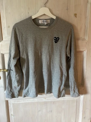  Comme des Garçons long sleeve - Grå långärmad tröja från Comme des Garçons PLAY med rund hals och svart hjärt-detalj på bröstet. Pris kan diskuteras vid snabb affär!