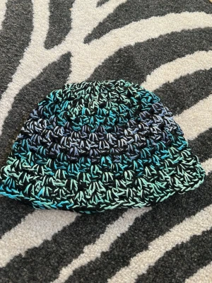 Handvirkad bucket hat i blå toner - Unik handvirkad bucket hat i svart och blåskiftande bomullsgarn. Sitter bra på mig med 55cm i omkrets på huvudet 