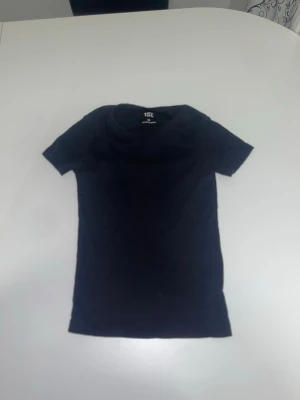Svart t-shirt från 157 i XS - En basic svart t-shirt från 157 i storlek XS. T-shirten är kortärmad och har en klassisk passform. Tillverkad i mjuk bomull med lite elastan för extra stretch och komfort. Perfekt till jeans eller shorts för en enkel och clean look.
