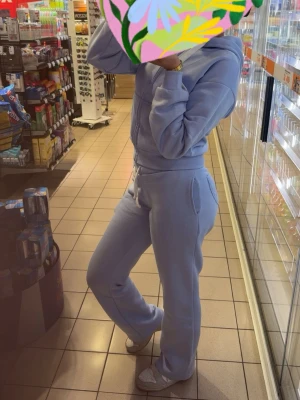 Ljusblått mjukisset med huva - Mysigt ljusblått loungewear-set med hoodie och matchande byxor. Hoodien har dragkedja och fickor, byxorna har resår i midjan och raka ben. Perfekt för chill dagar hemma eller när du vill vara bekväm och snygg. 