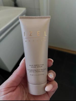 Izel Beauty Hair Shine Serum - Säljer ett hårserum från Izel Beauty som ger glans och stärker håret. Tuben är beige med guldfärgad text och rymmer 75 ml. Perfekt för dig som vill boosta hårets lyster och få en flawless finish. Öppen och använd en gång. 