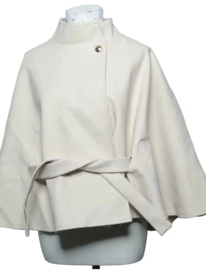 Krämvit cape-kappa med bälte - Stilren cape-kappa i krämvitt tyg med hög krage och dekorativ knapp ( aldrig använt). Kappan har ett matchande midjebälte och vida ärmar för en avslappnad men elegant look. Perfekt för dig som vill ha en trendig och unik ytterjacka. Materialet är mjukt och skönt. 