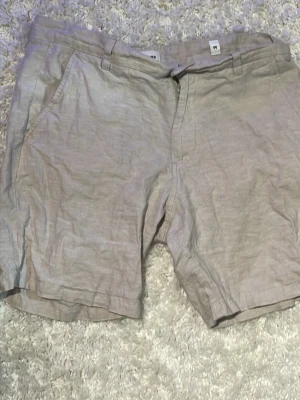 Beige linne-shorts med fickor - Snygga beige shorts i linne med klassisk passform. De har sidofickor fram och två bakfickor med knapp. Perfekta för varma dagar och har en stilren look som funkar till det mesta.