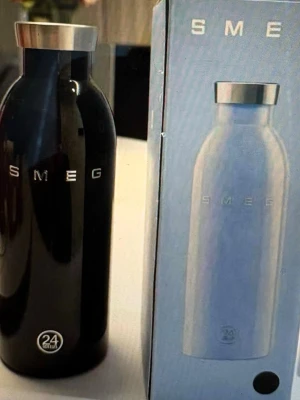Svart termos - Stilren svart vattenflaska med silverfärgat skruvlock. Flaskan är tillverkad i rostfritt stål och har SMEG-loggan i silver på framsidan. Perfekt för att hålla drycken kall eller varm i upp till 24 timmar.
