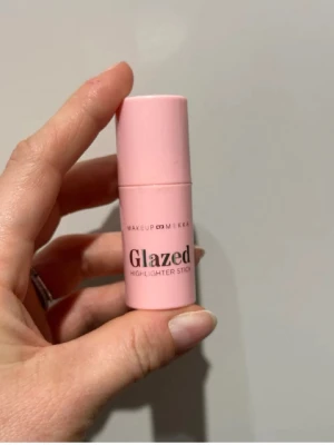 Glazed Highlighter Stick rosa - Glazed Highlighter Stick från Makeup Mekka i en söt rosa hylsa. Highlightern har en skimrande, ljusrosa ton och kommer i praktiskt stiftformat som är lätt att applicera direkt på huden. Perfekt för att ge glow till kindben och brynben. Endast swatchad 