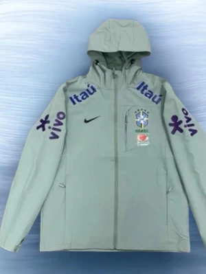 Grön Brasilien Nike träningsjacka/ vindjacka - Grön träningsjacka från Nike med Brasilien CBF-logga, gula Nike-loggan och sponsortryck i gult och vitt. Jackan har huva med dragsko, hel dragkedja och fickor. Perfekt för fotbollsträning eller sportiga dagar.