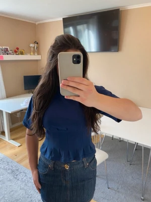 Mörkblå blus med veckad midja - Snygg mörkblå blus med korta ärmar och rund hals. Toppen har en figurnära passform och fina veckdetaljer vid midjan som ger en cool siluett. Perfekt att styla med jeans eller kjol för en trendig look! Använd någon enstaka gång men hoppas att de kan göra någon annan glad 🤍💙