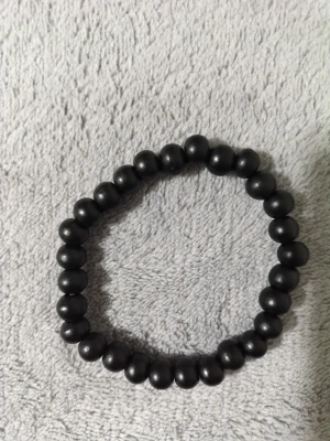 Svart pärlarmband i enkel design - Stilrent armband med svarta runda pärlor trädda på elastisk tråd. Perfekt accessoar för att ge din outfit en cool och minimalistisk touch. Passar både ensam eller i kombination med andra armband.