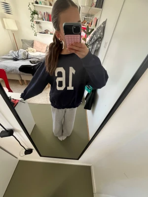 Mörkblå hoodie med tryck - Säljer en mörkblå hoodie med stort vitt tryck av siffran 16 på framsidan. Hoodien har en avslappnad passform och långa ärmar. Perfekt för en sportig och chill stil. Materialet känns mjukt och bekvämt mot huden.