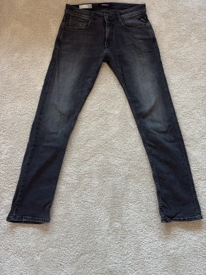 Svarta Replay jeans med smal passform - Snygga svarta jeans från Replay med smal passform och klassisk femficksdesign. Jeansen har tvättade detaljer för en cool look. Tillverkade i mjukt denimtyg som ger bra komfort och stil. En ytterst liten defekt på baksidan