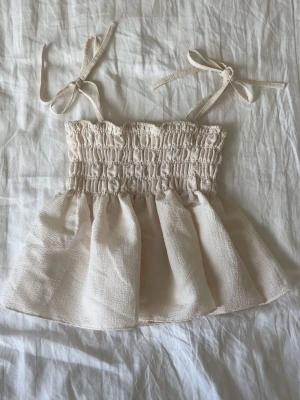 Linne Beige/Benvit   - Sött linne med rosett knyten!🤍Tröjan är köpt från ett koreanskt märke så storleken kan anses som ett snäpp mindre än vad de säger.