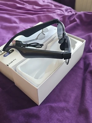XG88 Pro smarta glasögon svart... very good in music 🎶 u will enjoy it. - Säljer ett par svarta smarta glasögon XG88 Pro med inbyggda trådlösa hörlurar. Glasögonen har en modern design med mattsvarta bågar och mörka linser. Perfekt för att lyssna på musik eller ta samtal direkt via glasögonen. USB-laddkabel medföljer.