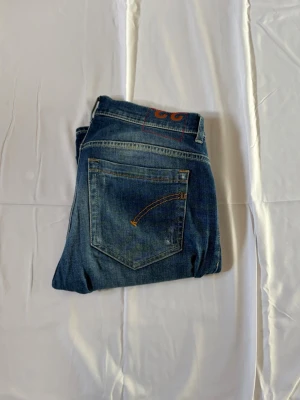  Dondup jeans - Säljer ett par blå jeans från dondup med slitningar och tvättade detaljer. Jeansen har klassisk femficksmodell, normal midja och smal passform. Snygga kontrastsömmar och en cool vintage-look gör dem perfekta till vardagsstilen. Modellen är 178 cm